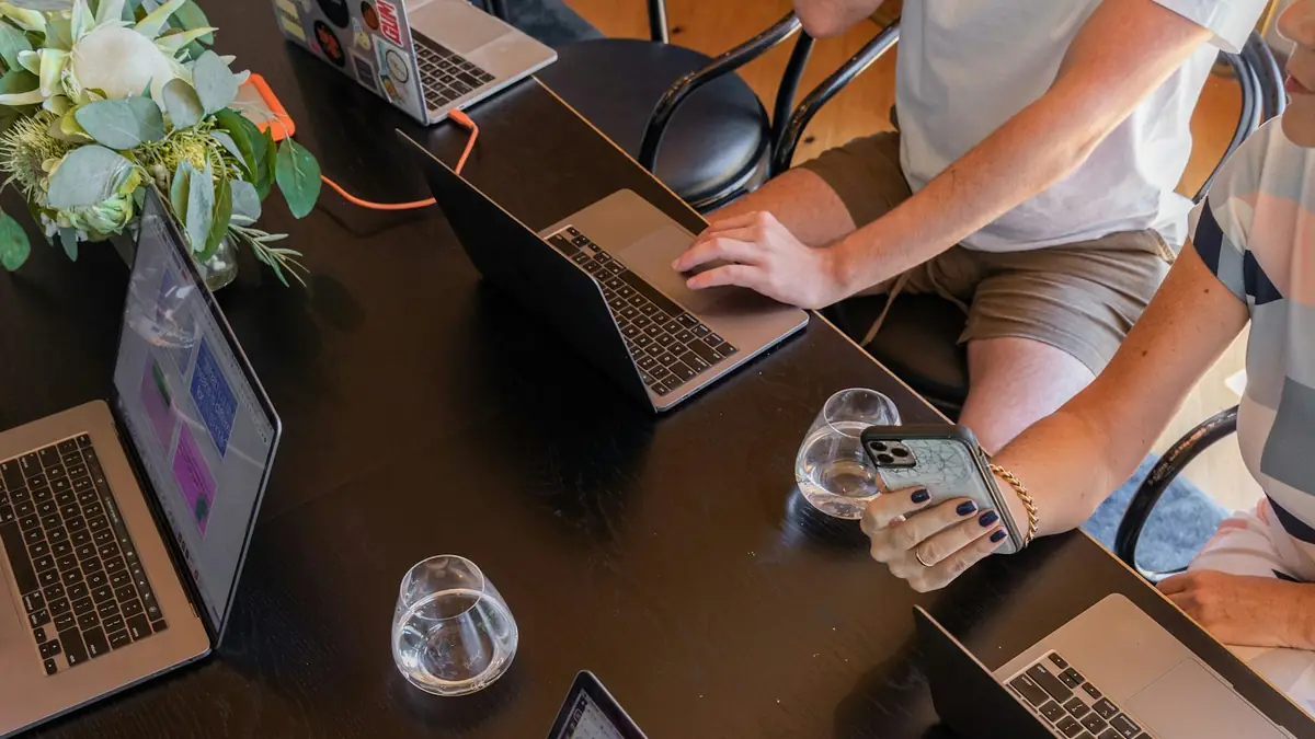 Equipo reunido alrededor de una mesa con computadoras planeando contenido