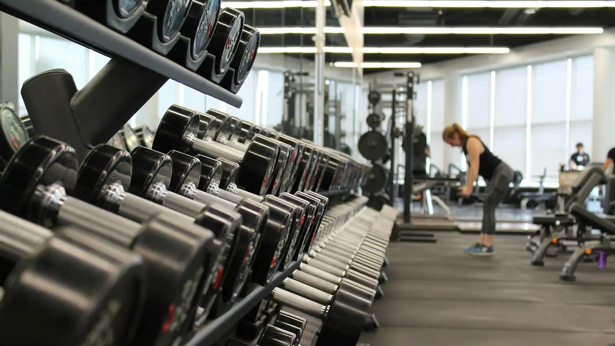 Mujer entrenando en un gimnasio rodeada de equipos de ejercicio