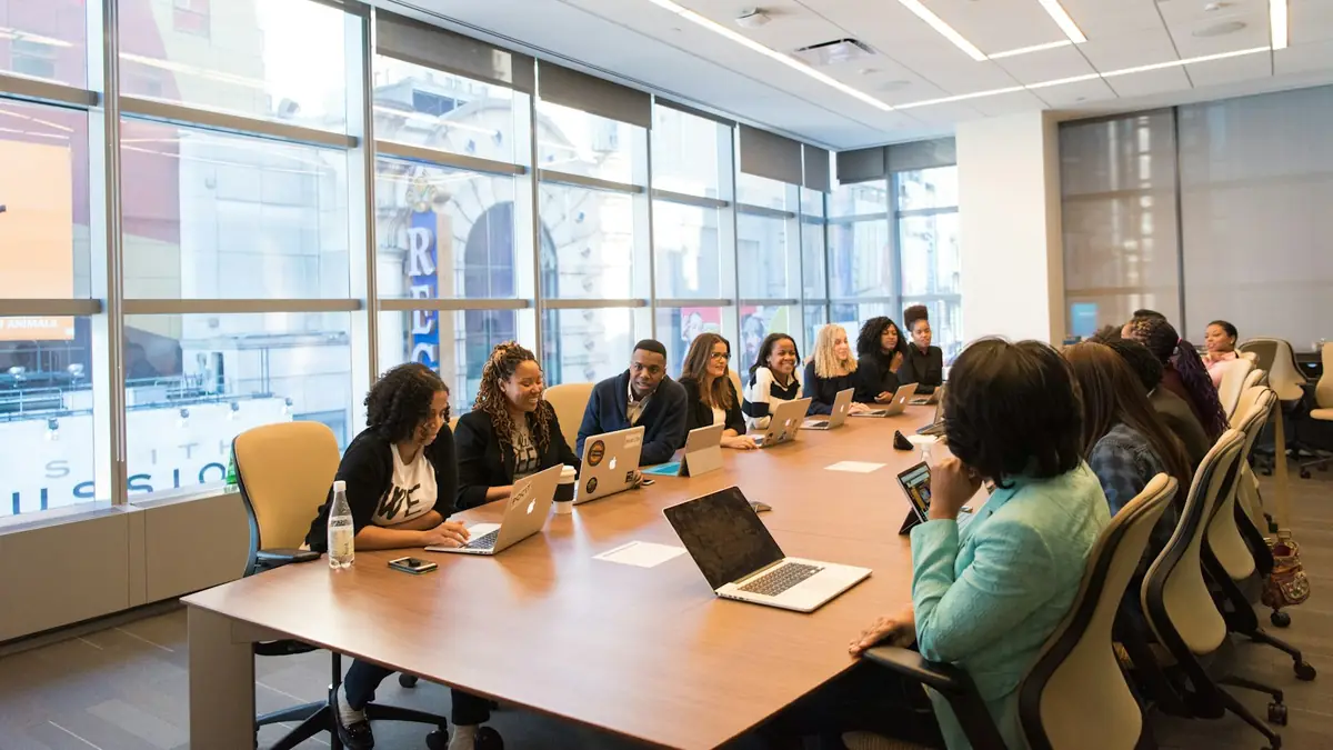 Equipo de ventas reunido alrededor de una mesa con portátiles