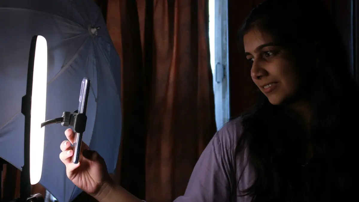 Mujer sosteniendo un teléfono frente a una luz de aro para grabar