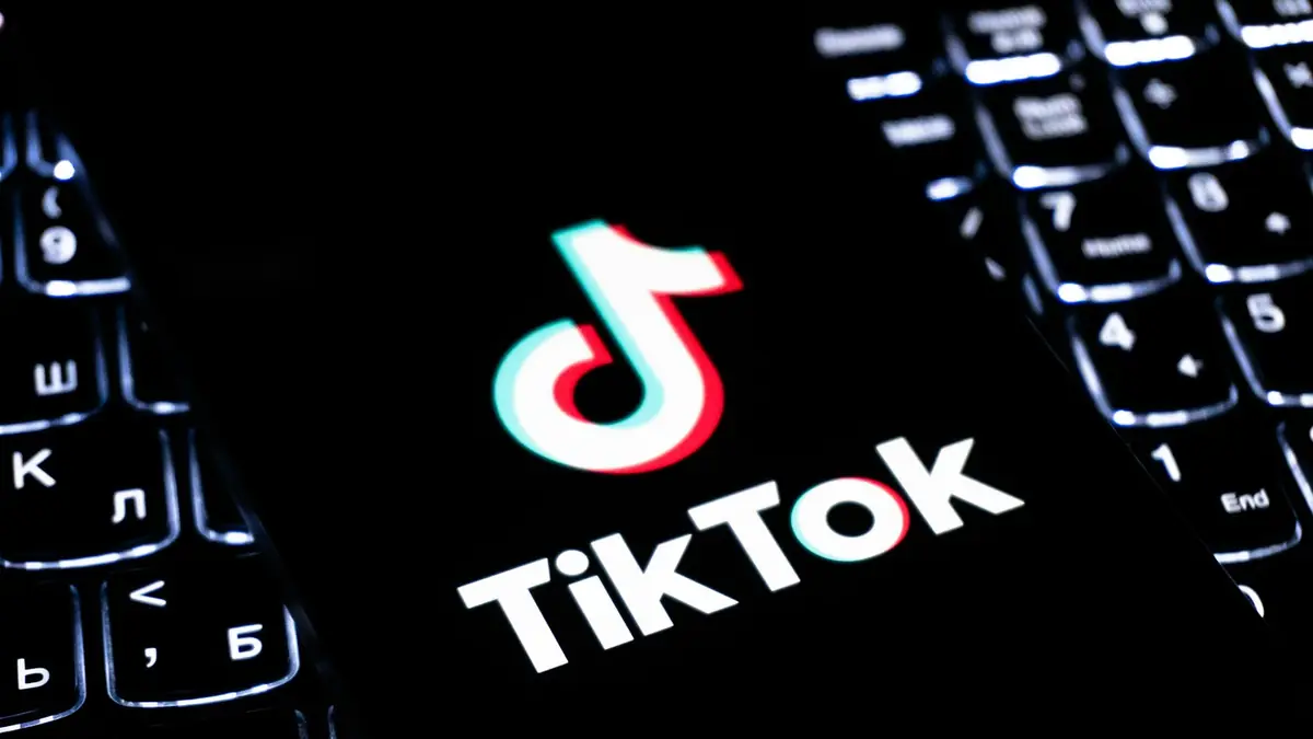 TikTok logo on a screen next to a backlit keyboard
