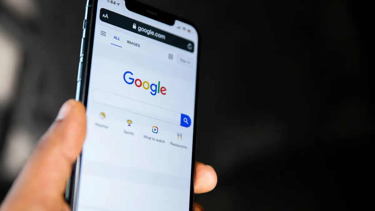 Hand holding a phone with the Google page open