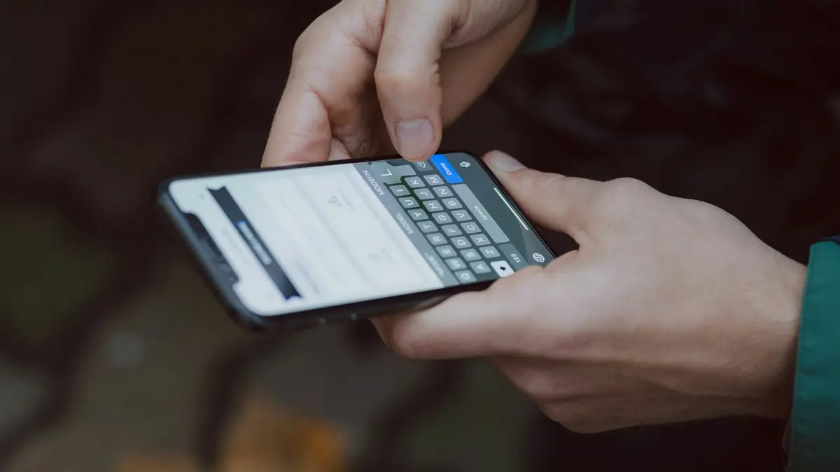 Mãos digitando uma mensagem em um celular