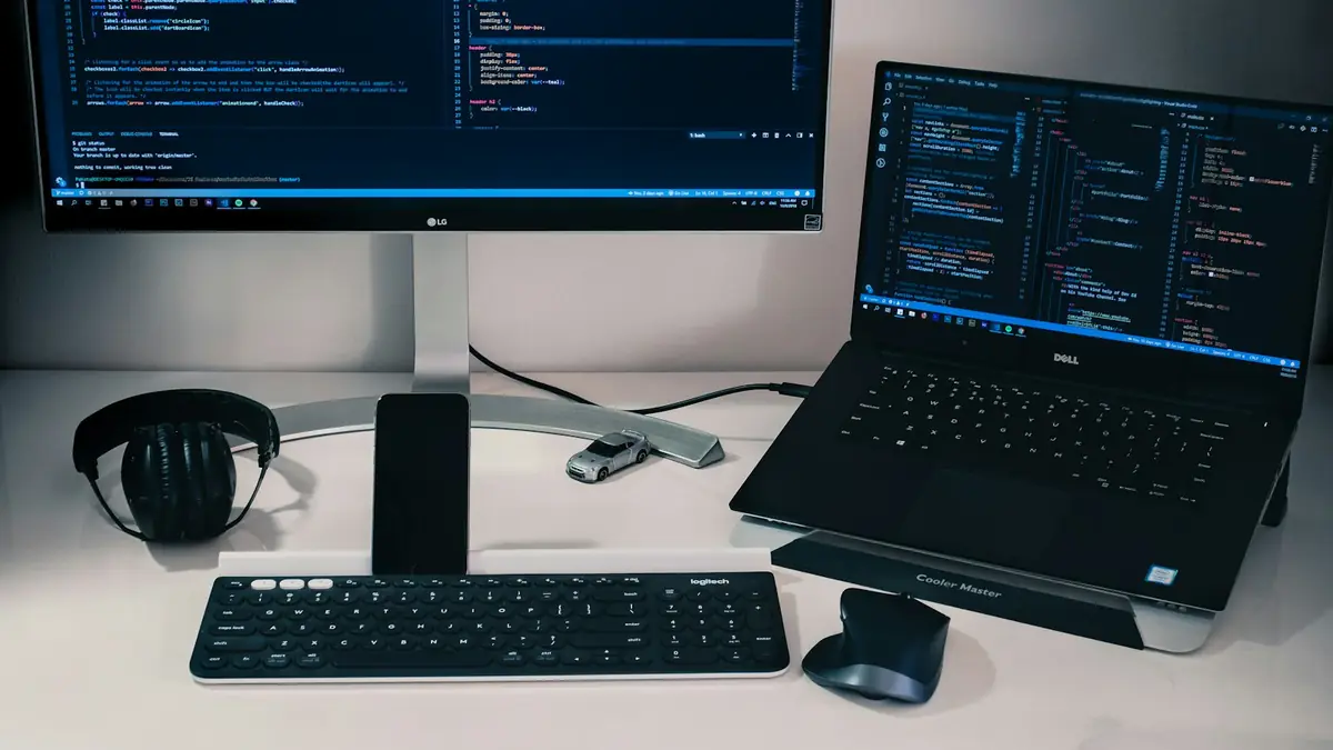 Escritorio con monitor y portátil mostrando código