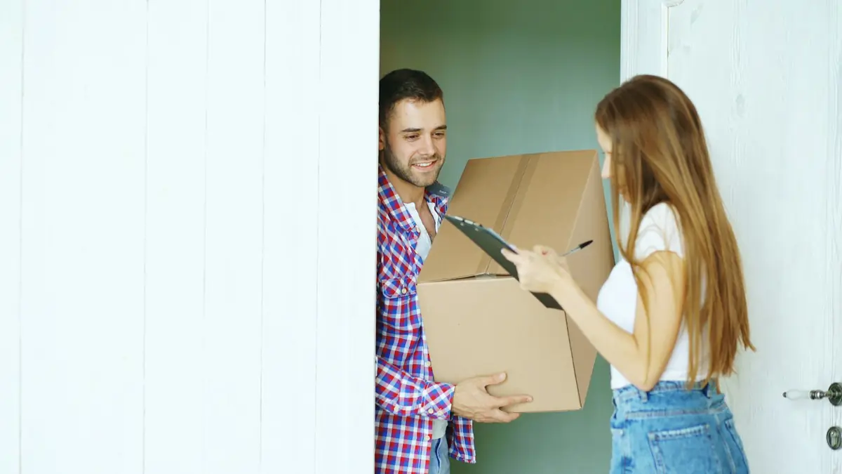 Pareja recibiendo la entrega de un paquete en la puerta de su casa