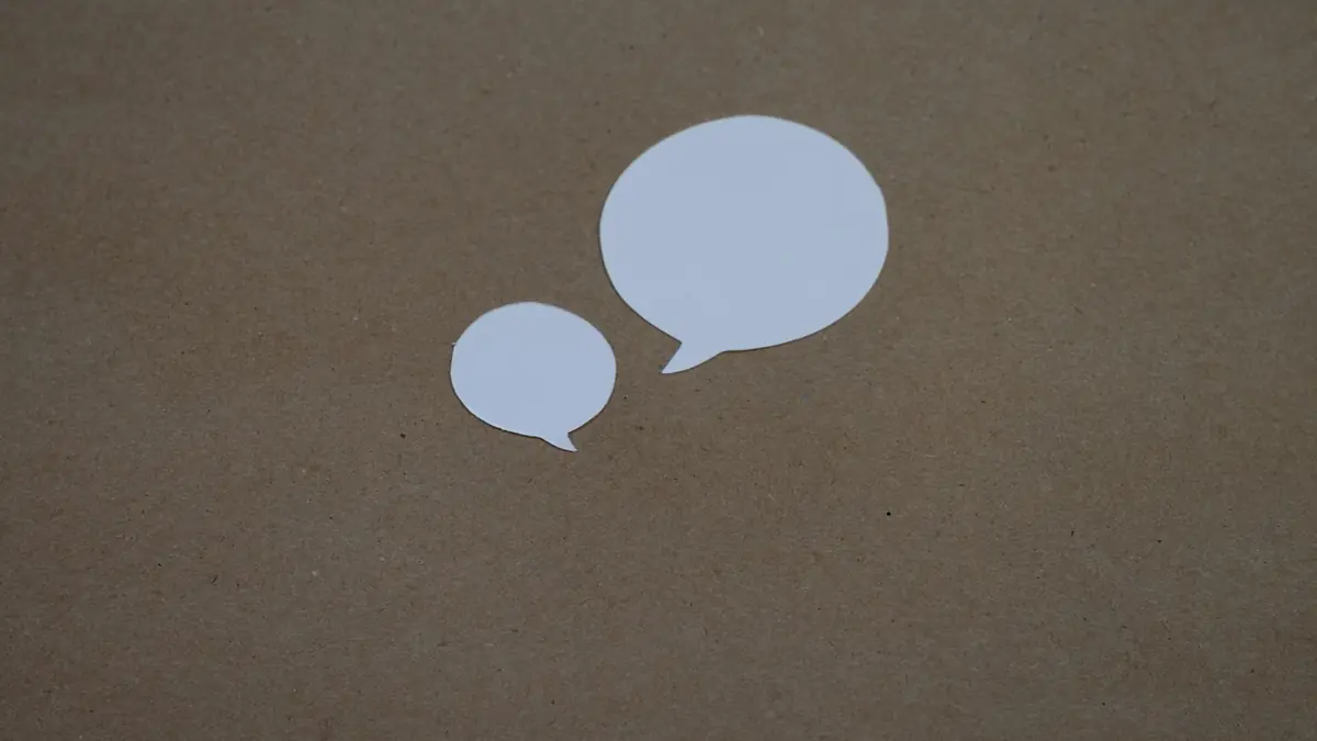 Dos globos de diálogo de papel blanco sobre un fondo café