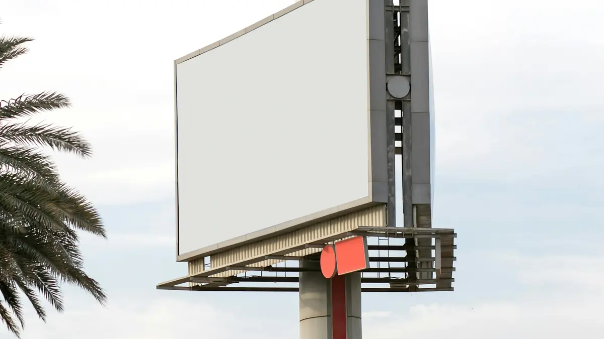Valla publicitaria en blanco junto a una palmera