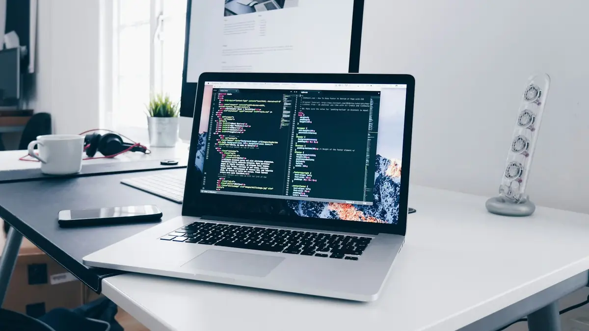 Portátil con código en pantalla sobre un escritorio de trabajo
