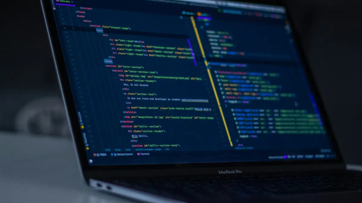 Portátil con código de programación abierto en un escritorio oscuro