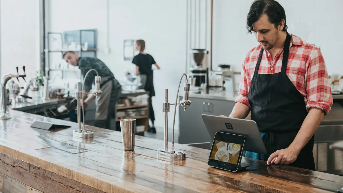 Barista usando una tableta en el mostrador de una cafetería