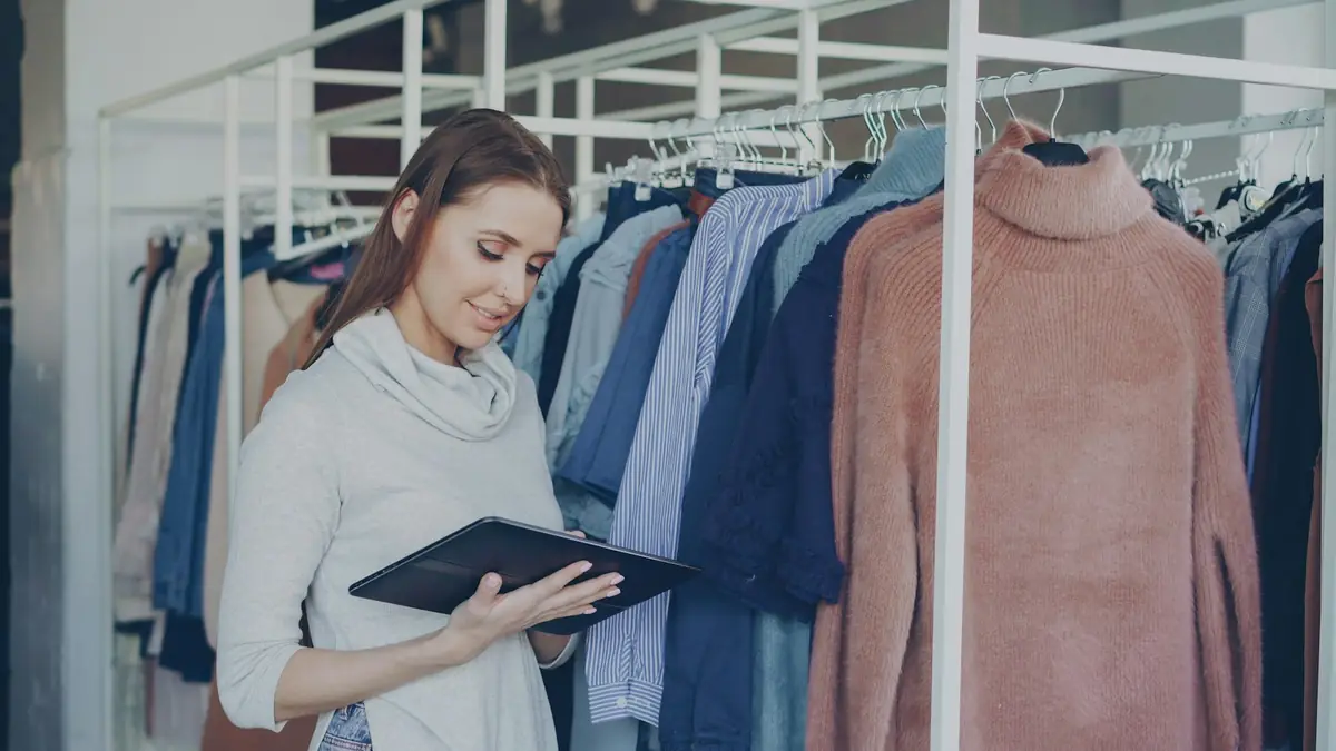 Clothing store owner using a tablet among the clothing racks