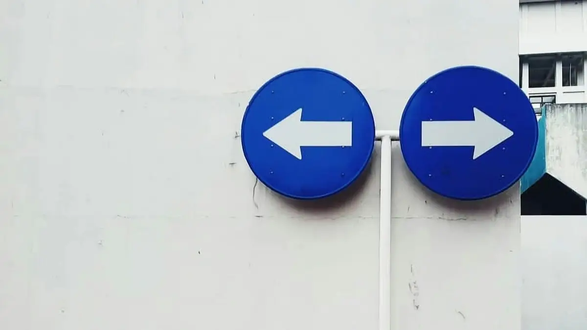 Dos flechas azules que apuntan en direcciones opuestas sobre una pared