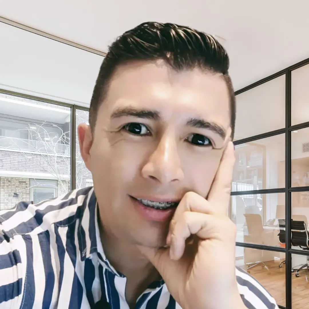 Edgar Jaimes sonriente con camisa a rayas azules y blancas, con brackets en los dientes, posando en una oficina moderna con paredes de vidrio.